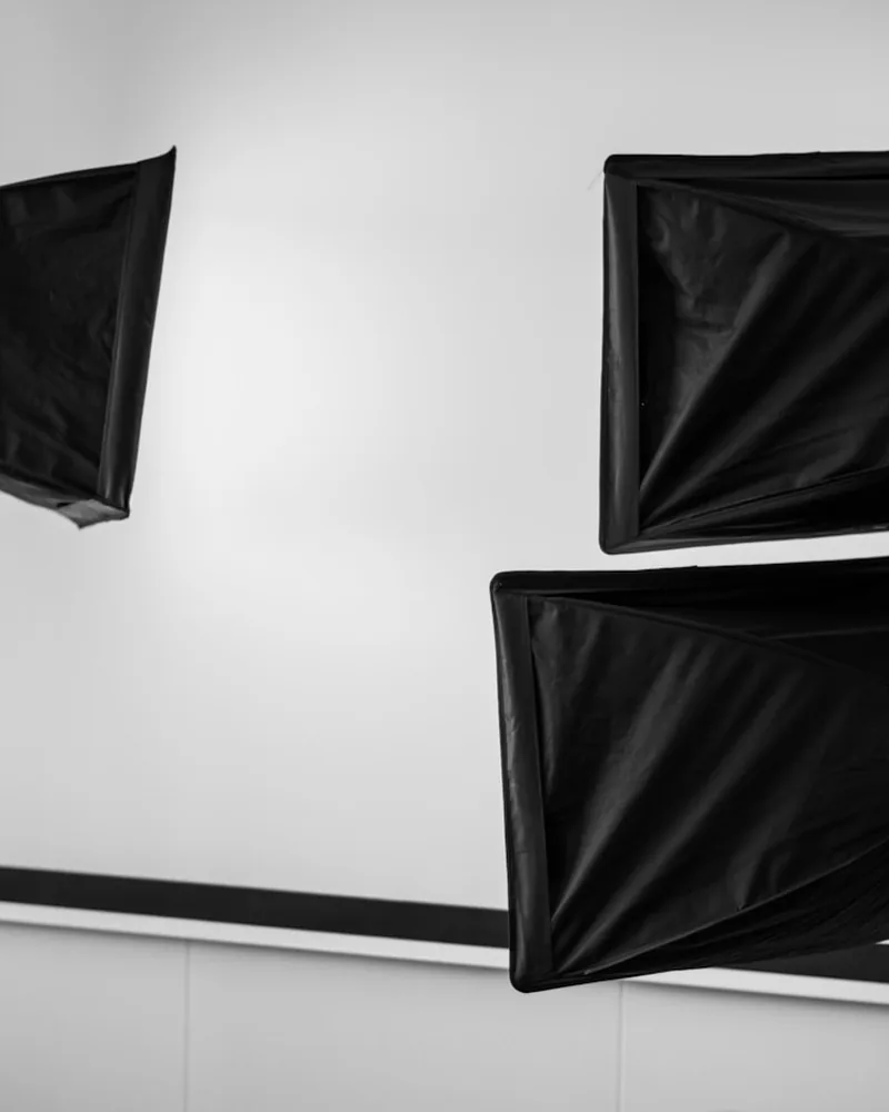 Tre softbox rettangolari sospesi sopra una parete chiara, visti dal basso